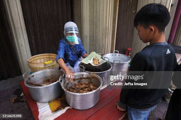 Seller wearing face shield serves "gudeg", a Yogyakarta traditional food to costumer amid COVID-19 outbreak in Yogyakarta, Indonesia. May 30, 2020....