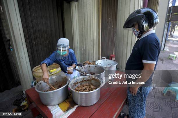 Seller wearing face shield serves "gudeg", a Yogyakarta traditional food to costumer amid COVID-19 outbreak in Yogyakarta, Indonesia. May 30, 2020....