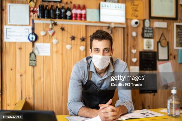 portrait of young small business man owner with face mask at checkout - small business mask stock pictures, royalty-free photos & images