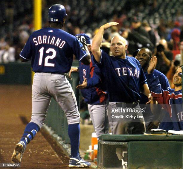 Alfonso Soriano of the Texas Rangers is greeted by Kevin Mench after hitting a leadoff solo home run in the 12th inning of 3-2 victory over the Los...