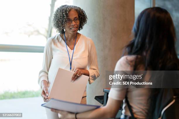 unrecognizable student speaks with mature female college professor - female lecturer stock pictures, royalty-free photos & images
