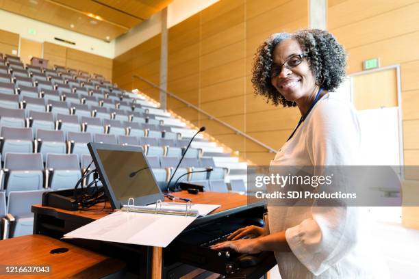 sonriente profesora universitaria hace una pausa de trabajo para posar para la foto - microphone desk fotografías e imágenes de stock