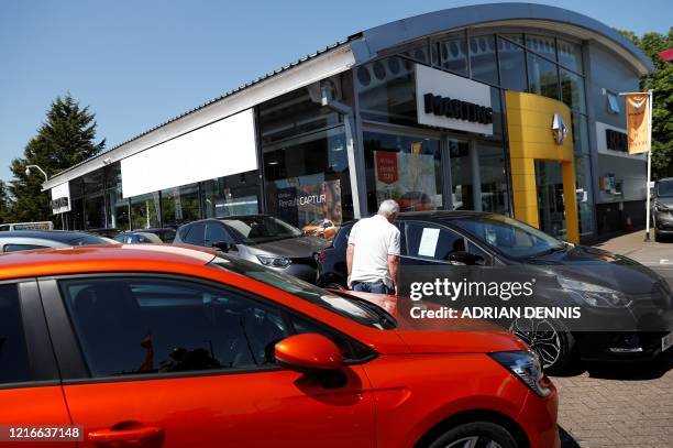 Customer looks at new and used cars displayed outside a re-opened Renault car dealership, in Old Basing, near Basingstoke southwest of London,...