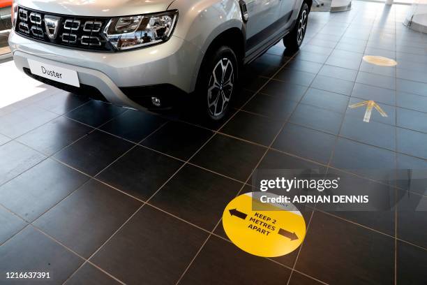 Floor stickers advising customers to social distance and stay two metres apart, are pictured next to a new Dacia Duster vehicle inside a re-opened...