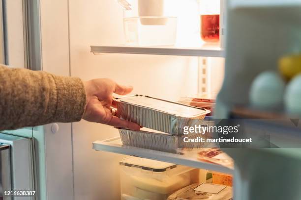 man's hand taking takeout meal out of refrigerator. - refrigerator stock pictures, royalty-free photos & images
