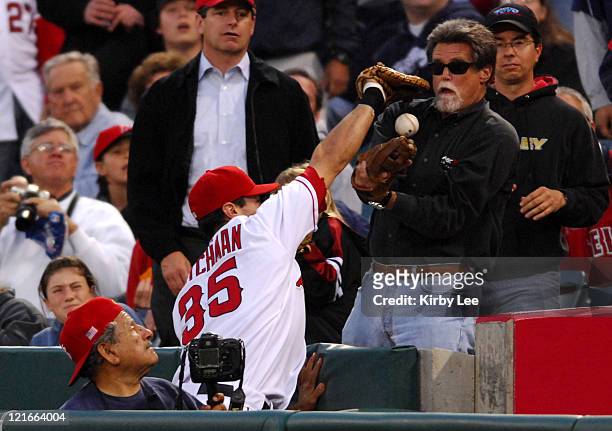 Casey Kotchman of the Los Angeles Angels collides with a fan while trying to catch a foul ball during Major League Baseball game against the Detroit...