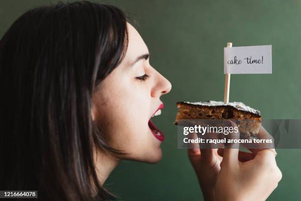 young woman holding a piece of cake holding a sign with the message "  cake time " with green background - cake flag stock pictures, royalty-free photos & images