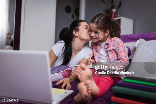 girl kissing younger sister when online learning with laptop - teen sibling stock pictures, royalty-free photos & images