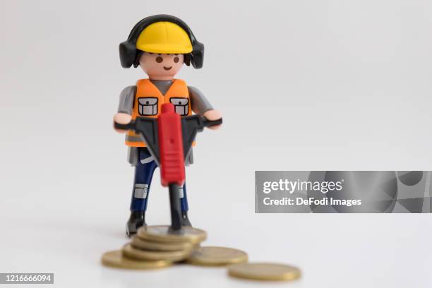 Playmobil figur construction worker "Fin" with pneumatic hammer with Euro coins are seen on April 03, 2020 in Dortmund, Germany.