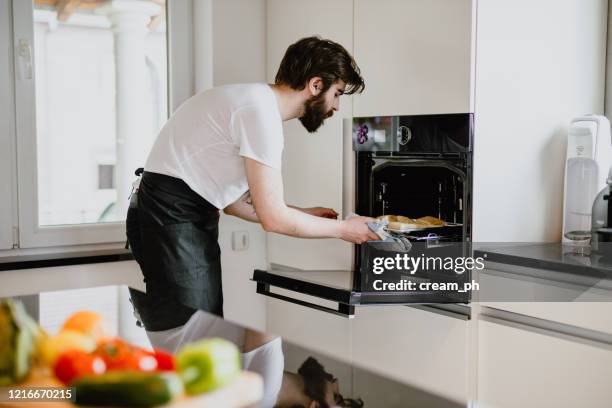 young man baking pastries in the kitchen at home - baking bread imagens e fotografias de stock