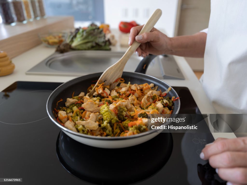 Unrecognizable woman at home cooking a chicken stir fry