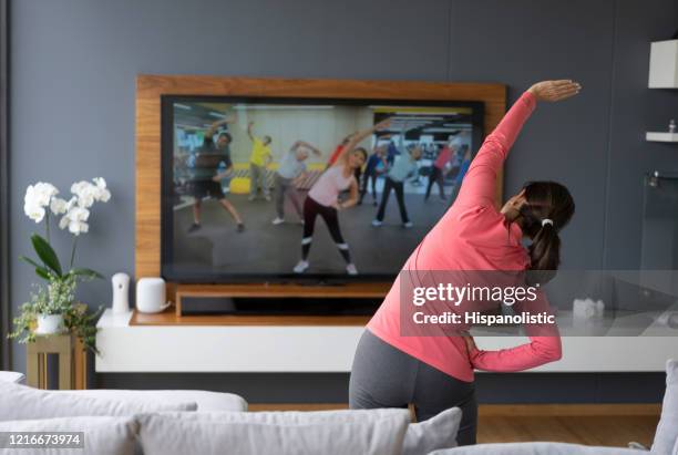 rückblick auf seniorin nach einer online-stretching-klasse mit blick auf den tv-bildschirm - aerobic stock-fotos und bilder