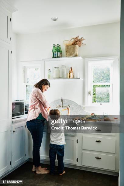 pregnant mother and young son washing vegetables at kitchen sink - women with health faucet stock pictures, royalty-free photos & images