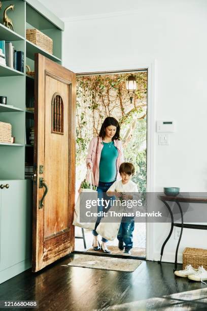 pregnant mother and young son carrying groceries in canvas bags into home - latin american and hispanic shopping bags stock pictures, royalty-free photos & images