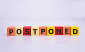 Postponed - words from wooden blocks with letters, postponed concept, top view background.