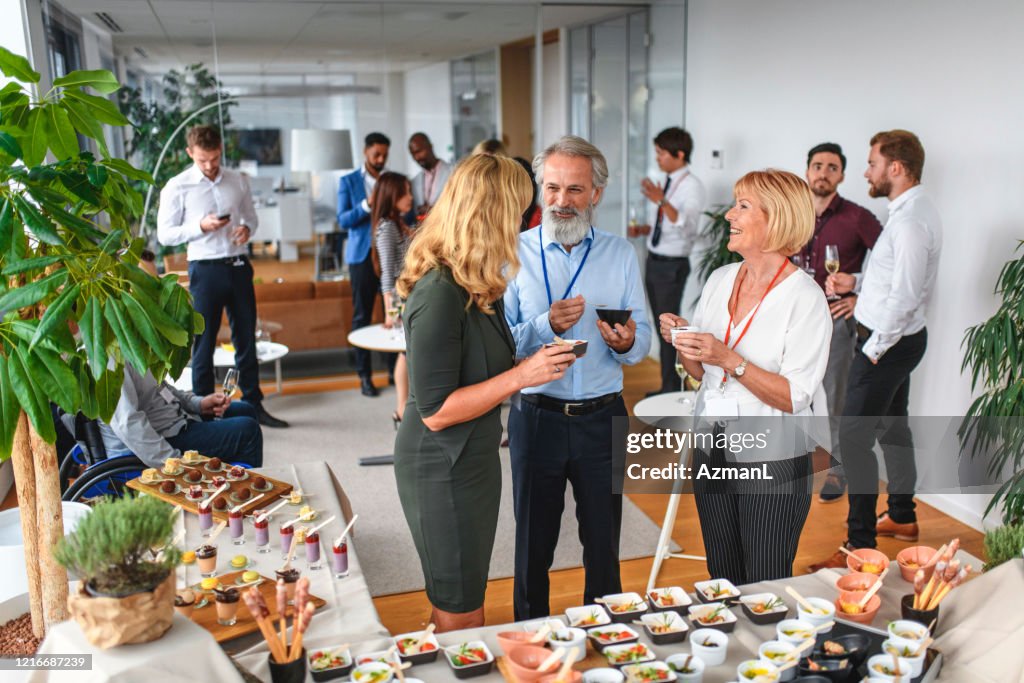 Smiling Colleagues Enjoying Food and Conversation at Party
