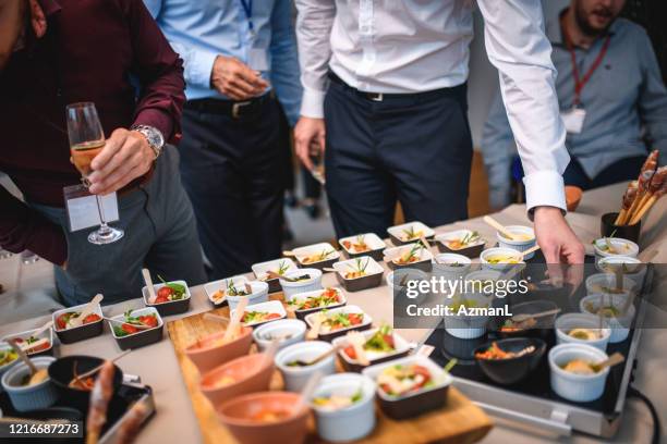 männliche führungskräfte wählen savory vorspeisen auf party - buffet stock-fotos und bilder