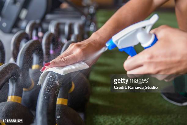 l'atleta pulisce e sanizza le attrezzature per il fitness prima dell'uso - squirt foto e immagini stock