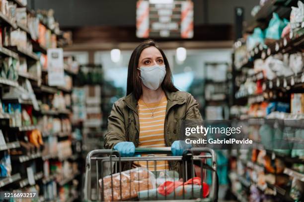 mujer empujando carrito de supermercado durante covid-19 - panic buying fotografías e imágenes de stock