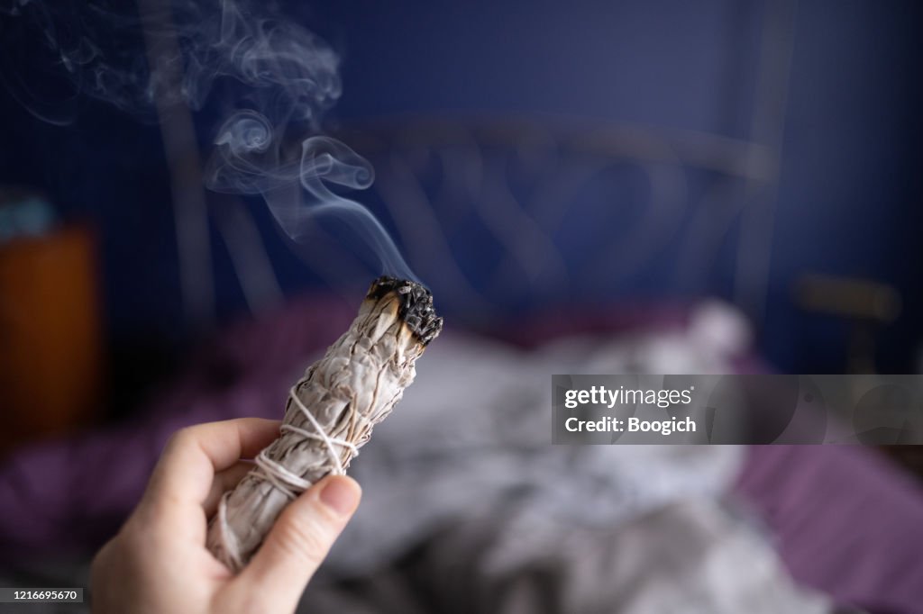 Frau reinigung die Luft durch Smudging Burning Sage Indoors in Miami Florida