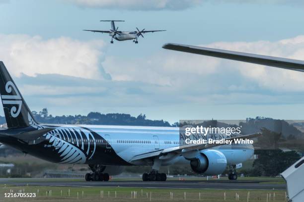 An Air New Zealand charter flight waits to leave Auckland International Airport as a domestic flight comes into land on April 04, 2020 in Auckland,...