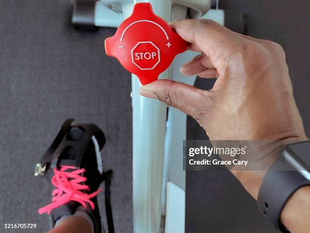 woman turns resistance knob on exercise bike - stop watch stockfoto's en -beelden