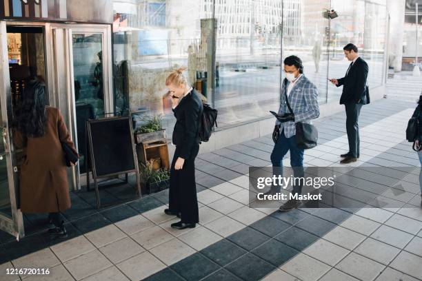 people standing in line outside cafe keeping distance - social distancing line stock pictures, royalty-free photos & images