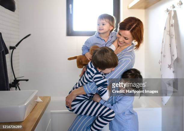 mother with small children indoors in bathroom in the morning at home, having fun. - brothers bathroom stock-fotos und bilder