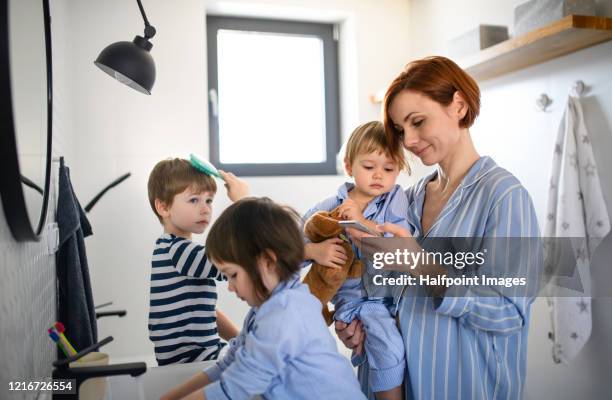 mother with three small children indoors in bathroom in the morning at home. - brothers bathroom stock-fotos und bilder