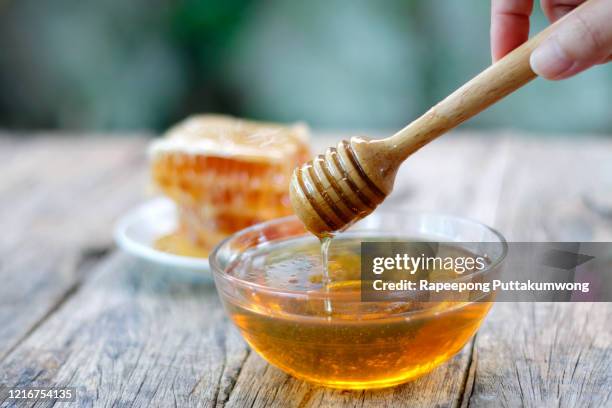 honey dipper and honeycomb on table - honey stockfoto's en -beelden