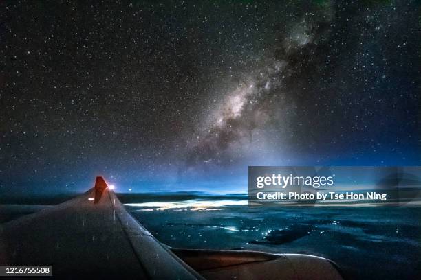 stunning milky way and city light with plane wing up on the sky - plane in sky stock-fotos und bilder