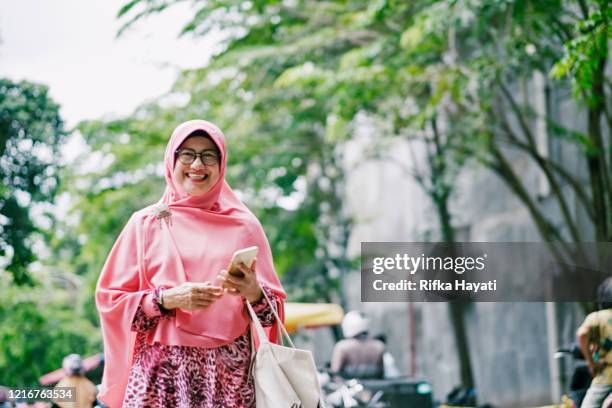 beautiful senior islam woman with mobile phone - indonesian ethnicity stock pictures, royalty-free photos & images