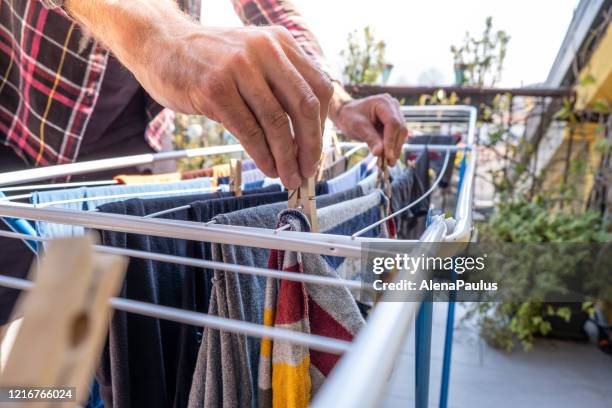 man hanging clothes on clothes line outdoors - washing line stock pictures, royalty-free photos & images