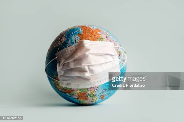 globe made of jigsaw puzzles with a protective medical mask - pandemic illness stock-fotos und bilder