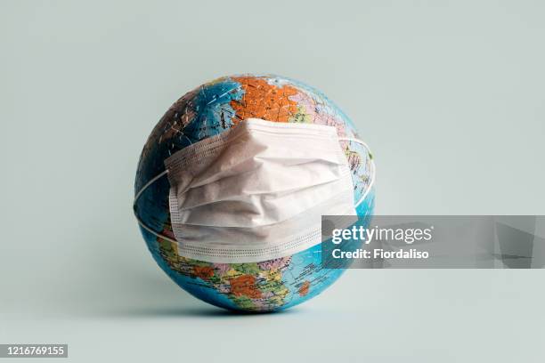 globe made of jigsaw puzzles with a protective medical mask - pandemia fotografías e imágenes de stock