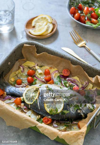 roasted sea bass with potatoes, herbs and tomatoes - lubina fotografías e imágenes de stock