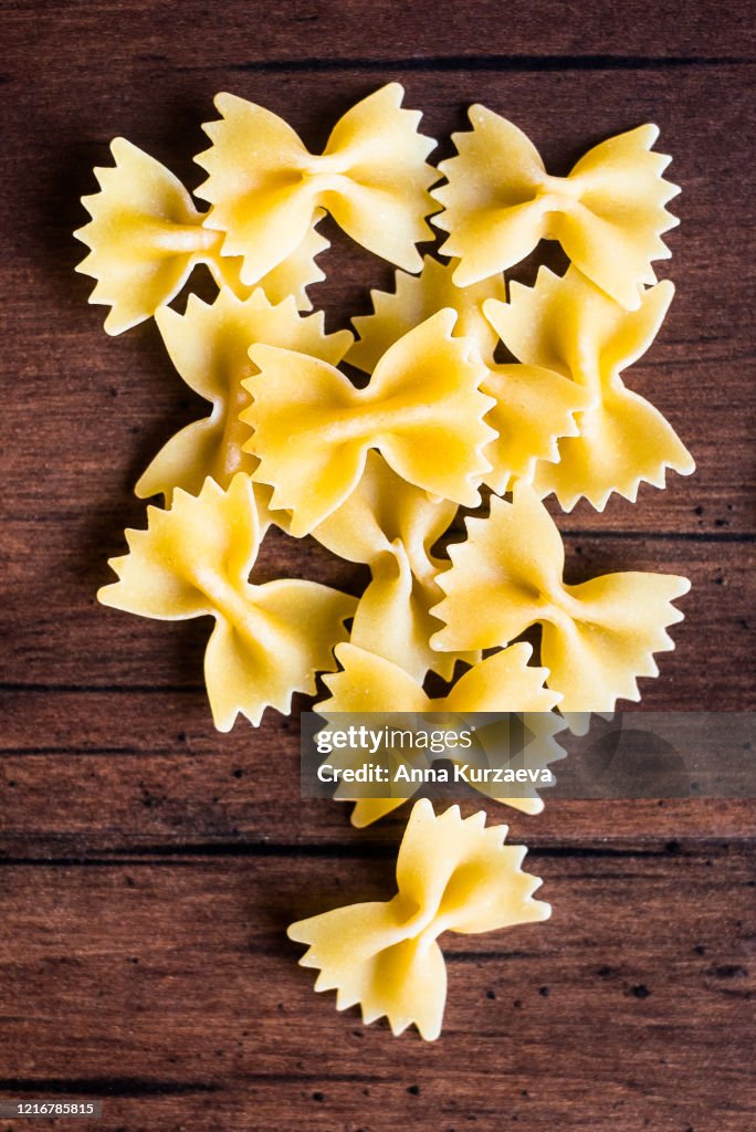 Heap of uncooked whole wheat farfalle or bow tie pasta italian pasta, top view. Pasta pattern. Food background.