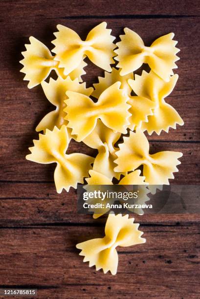 heap of uncooked whole wheat farfalle or bow tie pasta italian pasta, top view. pasta pattern. food background. - farfalle pasta stockfoto's en -beelden