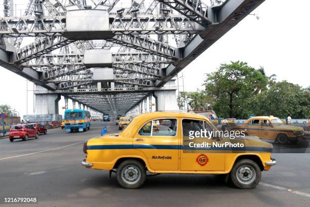 Yellow ambassador taxi drives past the Howrah Bridge after the government eased restrictions imposed as a preventive measure against the COVID-19...