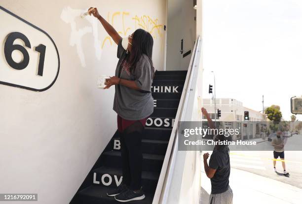 Angela Proctor, left, with her son Nikolas Steed, right, cover up graffiti on the building that houses Wayfarer, a social impact production company...