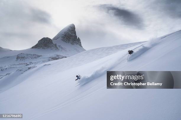 two skiers skiing off the wapta icefield - banff ski stock pictures, royalty-free photos & images