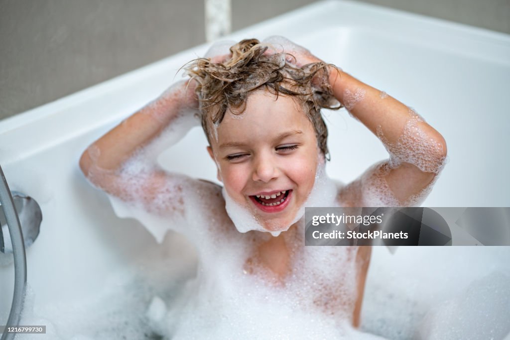Niño en bañera lavando el cabello