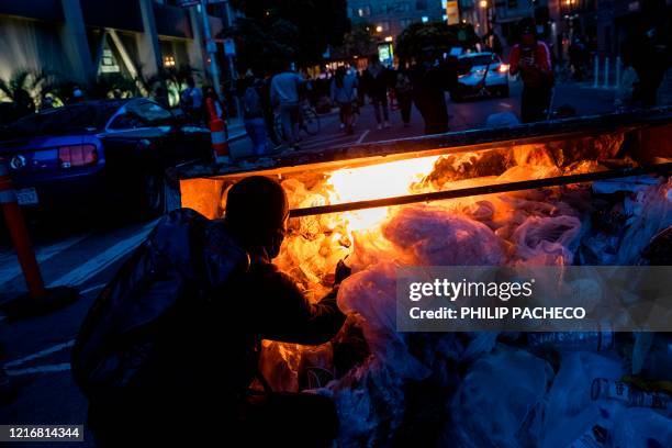 Straggling demonstrator lights a dumpster on fire after police disperse a largely peaceful crowd, following a protest over the police killing of...