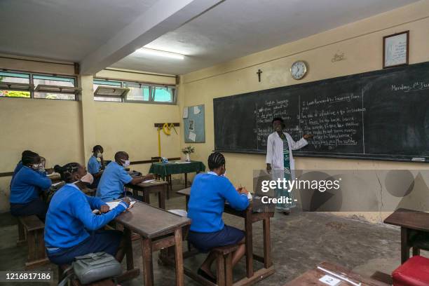 Students wear face masks and their teacher a face shield as a preventive measure against the spread of the COVID-19 coronavirus in their classroom at...