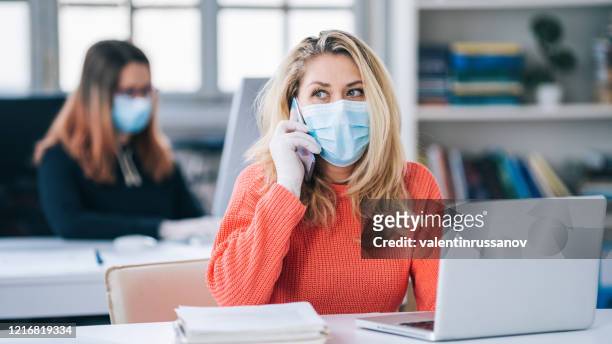 colleagues in the office working while wearing medical face mask during covid-19 - social distancing in office stock pictures, royalty-free photos & images