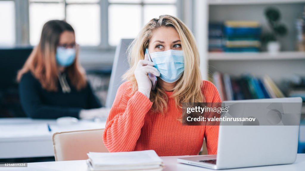 Kollegor på kontoret arbetar medan du bär medicinsk ansiktsmask under COVID-19