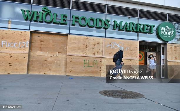 People go shopping at a Whole Foods Market store, which is boarded up after a night of protest over the death of African-American man George Floyd in...
