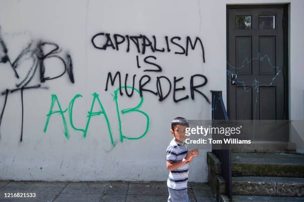 Child walks by graffiti on H St. NW, on Monday, June 1 after weekend protests sparked by the death of George Floyd occurred near the White House.