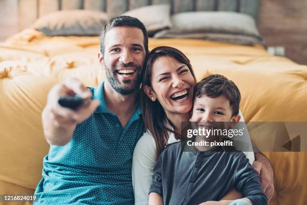 familia viendo la televisión juntos - pareja abrazados cama fotografías e imágenes de stock