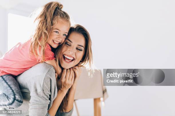 happy mom carrying her little daughter - piggyback stock pictures, royalty-free photos & images